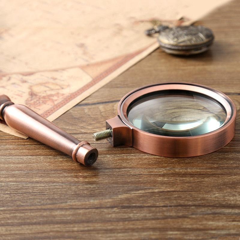 Examining Old Silver Coin Through Magnifying Glass On Wooden Table